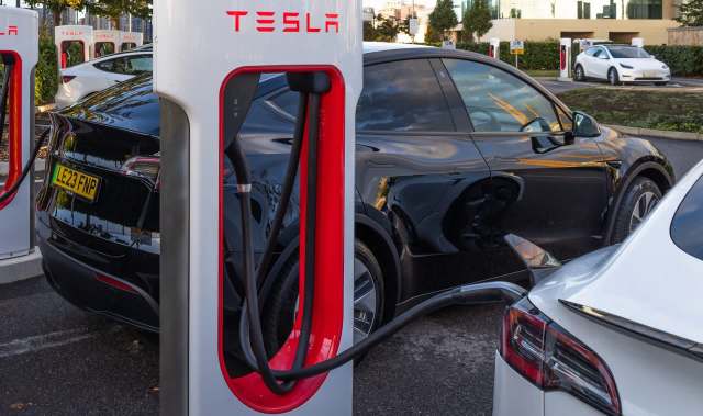 A black Tesla charging at a Supercharger station.