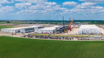 A bird's-eye view of a large construction site of a data center campus with cranes and parked cars in a rural landscape.