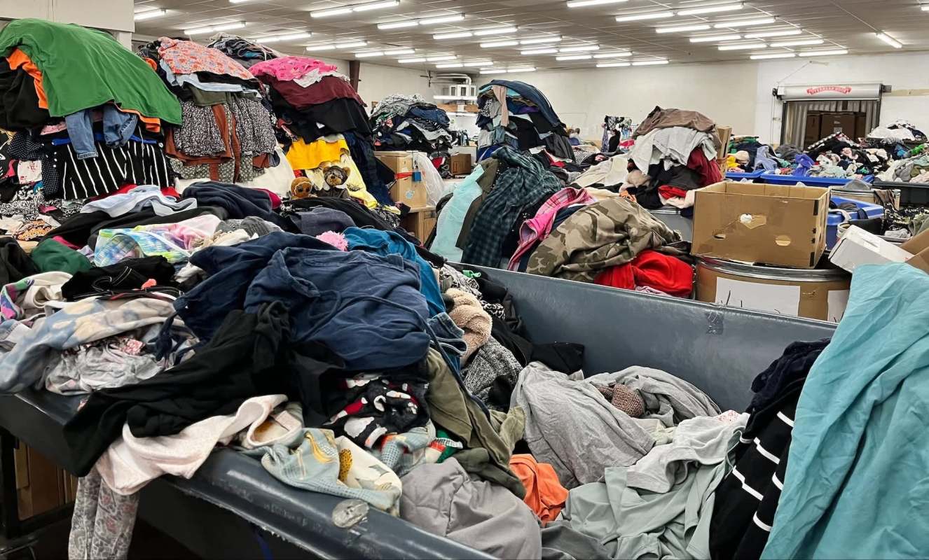 A room filled with piles of unorganized clothing.