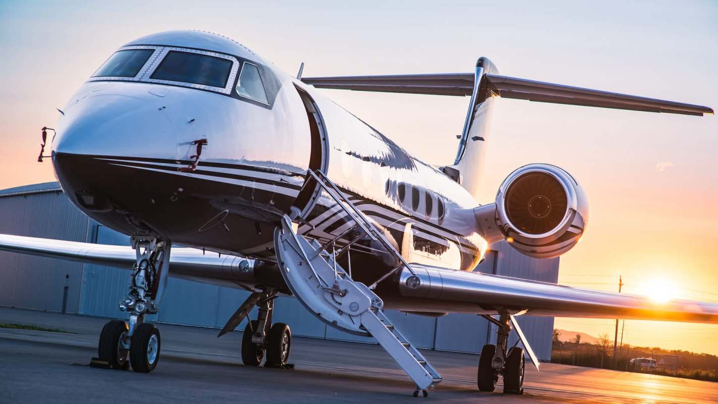 A sleek jet parked on a tarmac during sunset, showcasing its gleaming exterior and open boarding stairs.