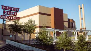 Target Field Station building with red signage, surrounded by trees and modern architectural features under a clear sky.