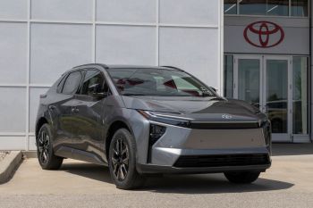 A gray Toyota SUV parked outside a dealership with a prominent Toyota logo in the background.