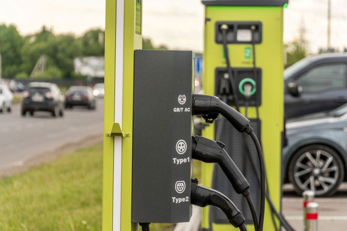 An electric vehicle charging station with multiple connectors alongside a busy road.