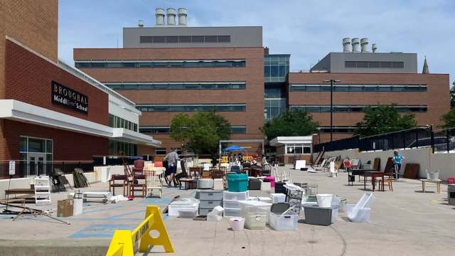 A school parking lot filled with various chairs and boxes during a community cleanup event.
