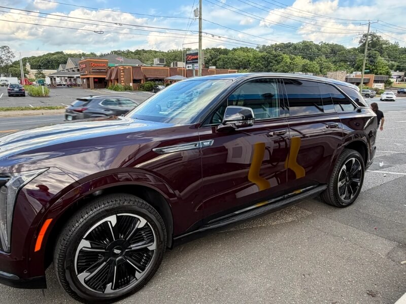 A maroon SUV with sleek black rims parked on a street with blurred vehicles in the background.