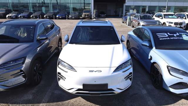 Three cars parked at a dealership, featuring a white BYD SUV flanked by a gray and a blue car.