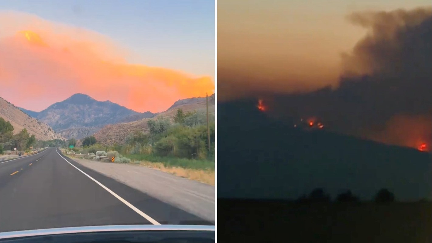 A road leading to mountains under a smoky sunset and flames on a distant hillside.