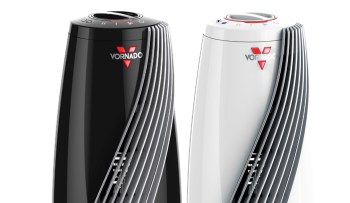 Two Vornado space heaters, one black and one white, featuring sleek designs and control knobs on top.