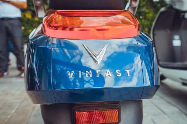 The rear view of a blue VinFast vehicle featuring a prominent logo and taillight.