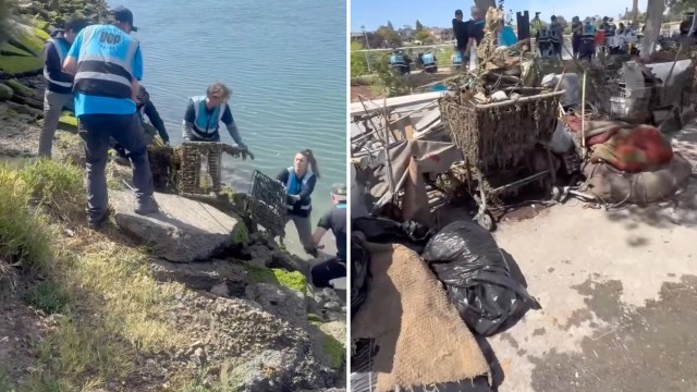 Volunteers remove trash and debris, including a shopping cart, from a riverbank.