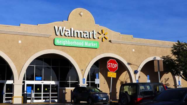 A Walmart Neighborhood Market storefront featuring a stop sign and blue skies above.