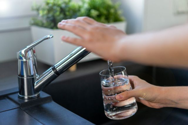 Filling a glass with water at the kitchen sink.