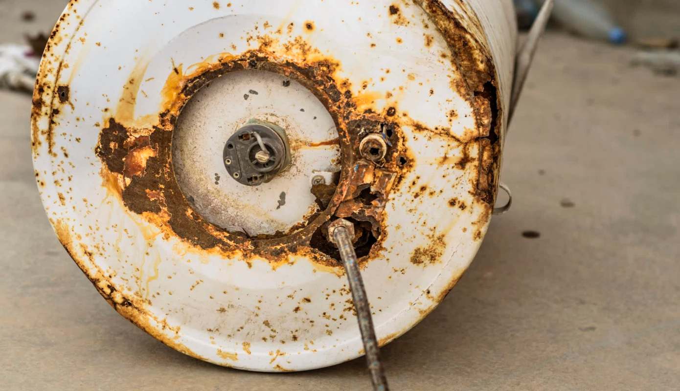 A rusty water heater with a corroded valve and cracked surface.