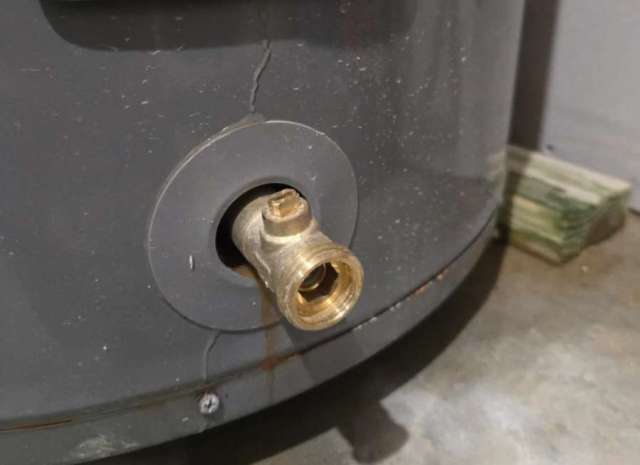 A brass fitting on the side of a gray water heater.