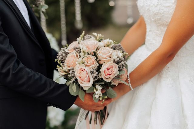 A bride and groom holding a bouquet of roses.