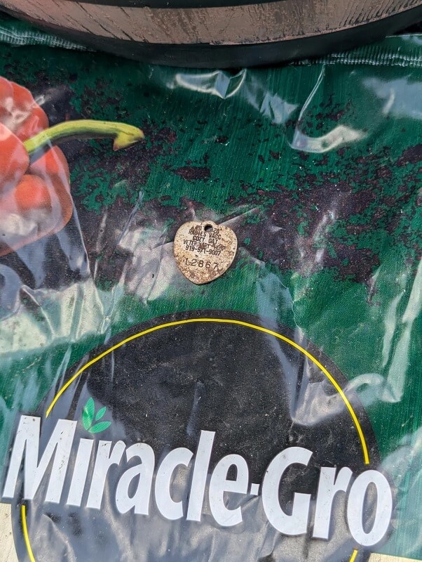 A Miracle-Gro fertilizer bag with a partially visible product label and dirt.