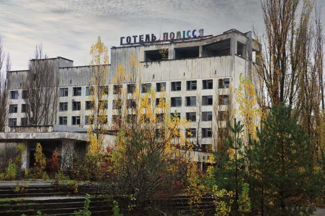An abandoned building surrounded by overgrown vegetation and trees.