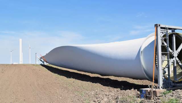 A wind turbine blade lies on dry ground.
