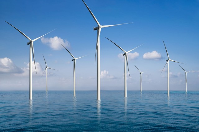A row of wind turbines in the ocean.