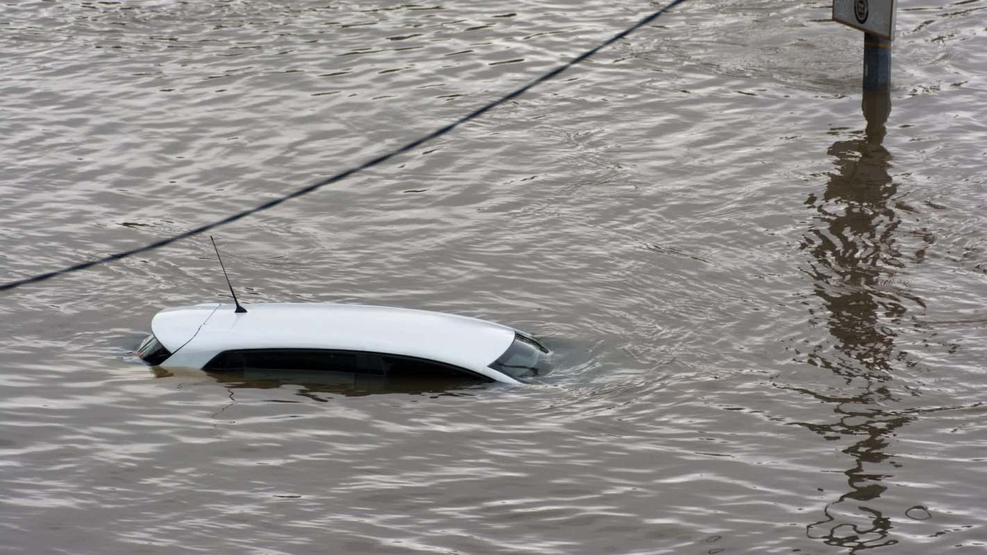 A white car partially submerged in floodwaters.