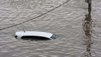 A white car partially submerged in floodwaters.