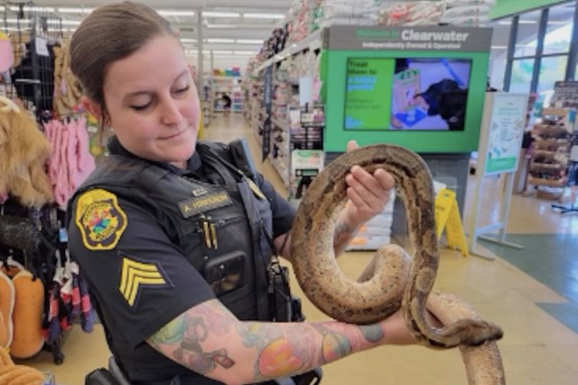 Police officer holds a snake in a store.