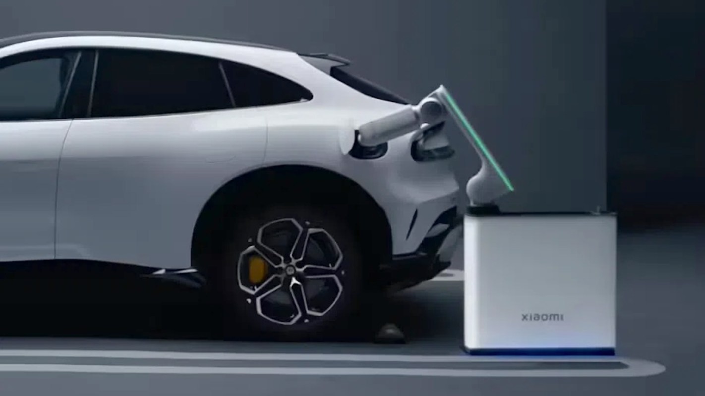 A white Xiaomi electric vehicle connected to a robotic battery-swapping station.