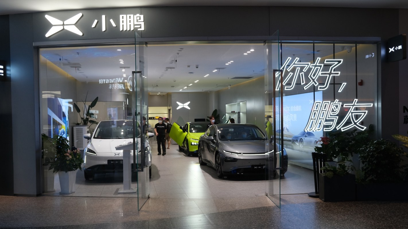A modern car showroom featuring electric vehicles and illuminated signage in a sleek interior space.