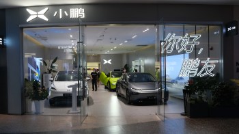 A modern car showroom featuring electric vehicles and illuminated signage in a sleek interior space.