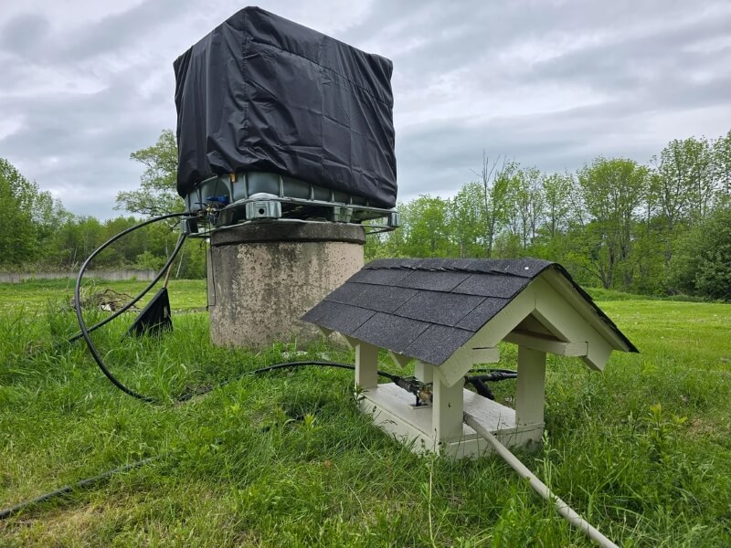 A large outdoor water tank with hoses leading off in multiple directions.