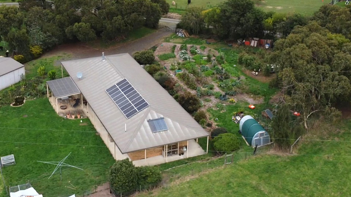 Aerial view of a house with solar panels and a garden.
