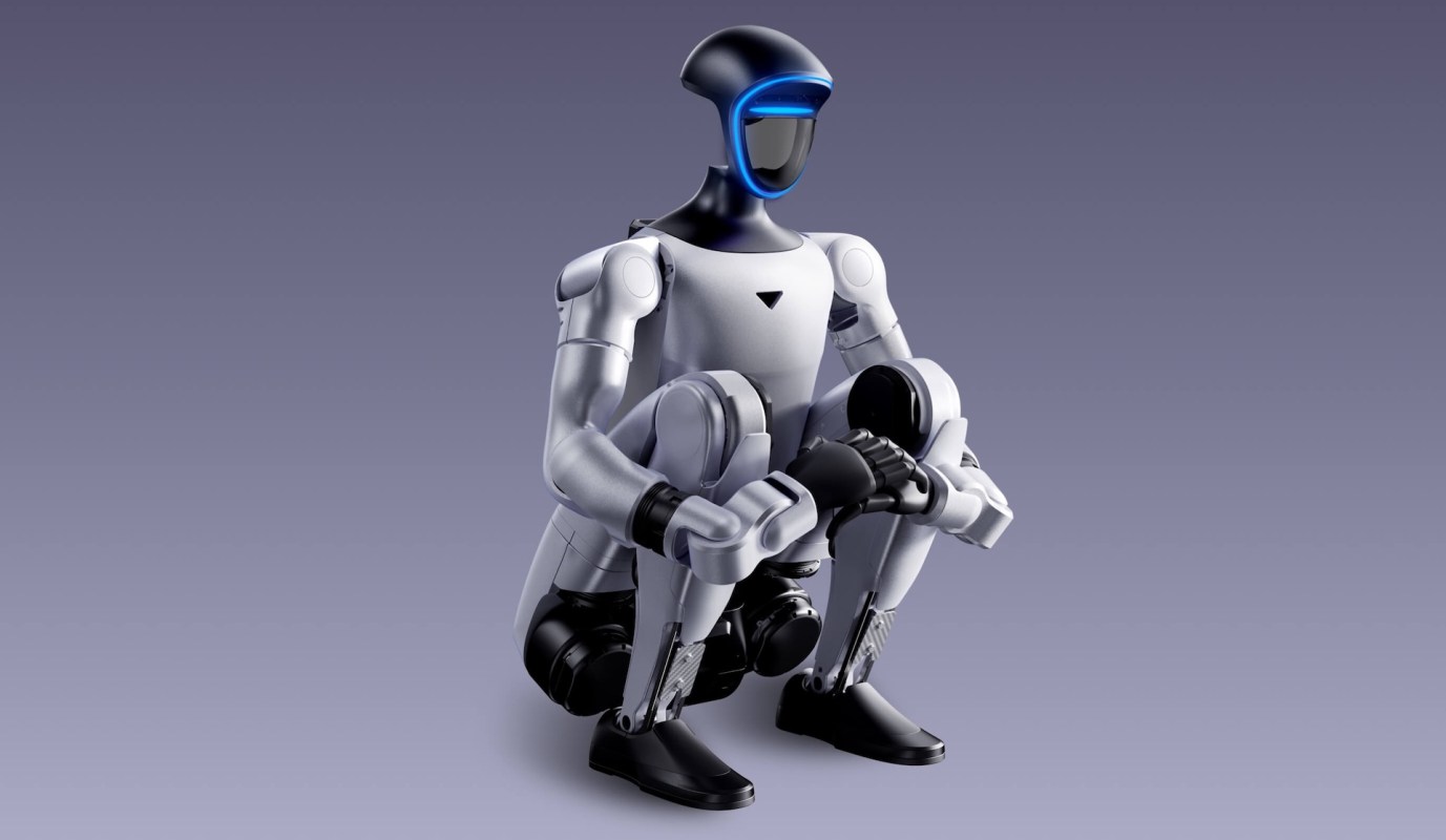 A humanoid robot with a sleek design squatting on a smooth surface against a gradient background.
