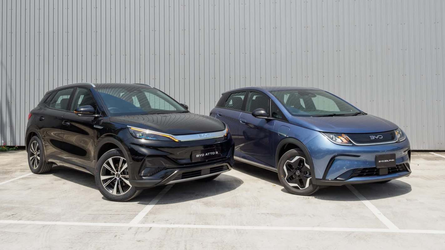 Two electric cars, a black BYD Atto 3 and a blue BYD Dolphin, parked side by side in front of a gray background.