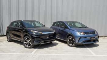 Two electric cars, a black BYD Atto 3 and a blue BYD Dolphin, parked side by side in front of a gray background.