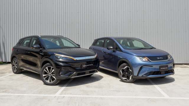 Two electric cars, a black BYD Atto 3 and a blue BYD Dolphin, parked side by side in front of a gray background.
