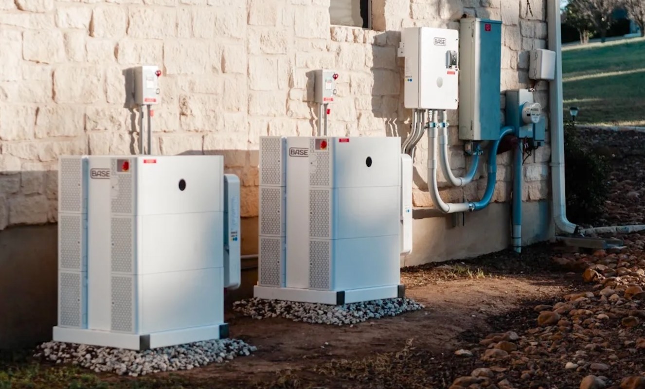 Two white utility boxes installed against a stone wall, featuring electrical components and connected pipes.