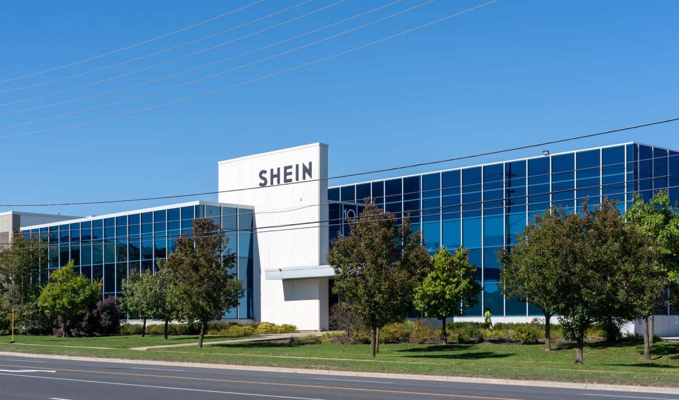 A modern building with large glass windows, featuring the name "SHEIN" prominently on its facade.