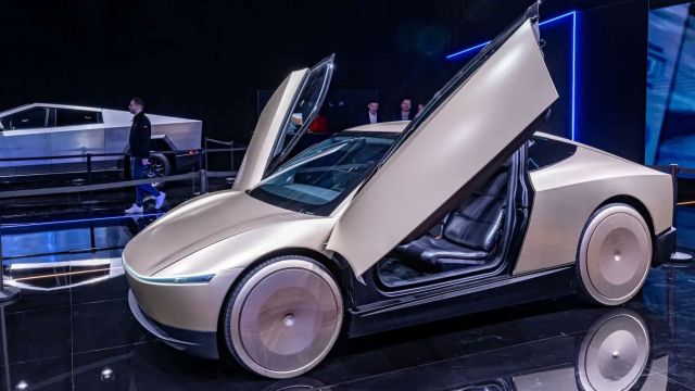 A futuristic car with gullwing doors showcased at an event, featuring sleek lines and unique wheels.