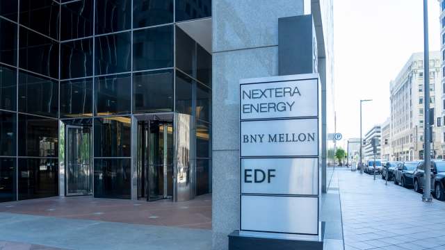 A modern glass building entrance featuring a sign with company names, including NextEra Energy.
