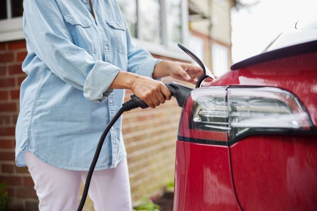 A woman plugging a charger into an EV.