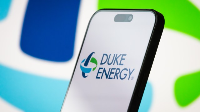 A smartphone displays the Duke Energy logo against a colorful background.