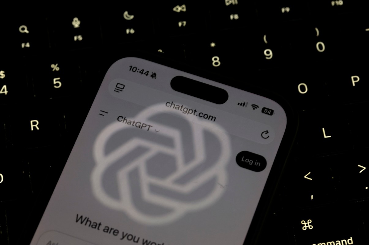 A smartphone displaying the ChatGPT website, illuminated against a dark keyboard background.