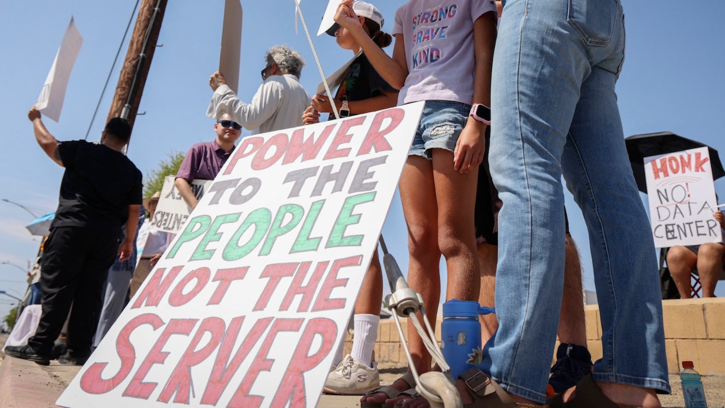 A group of people holding signs that promote a protest against a data center.