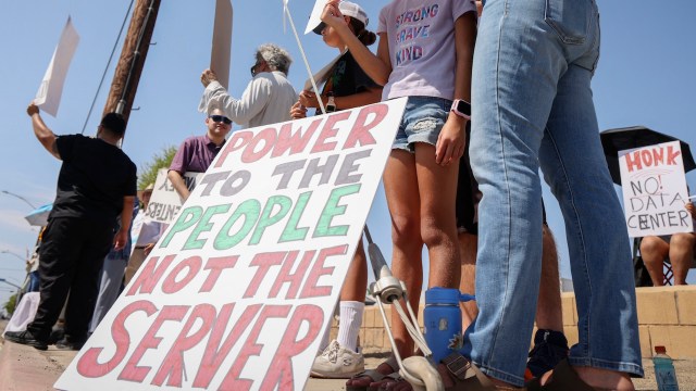 A group of people holding signs that promote a protest against a data center.