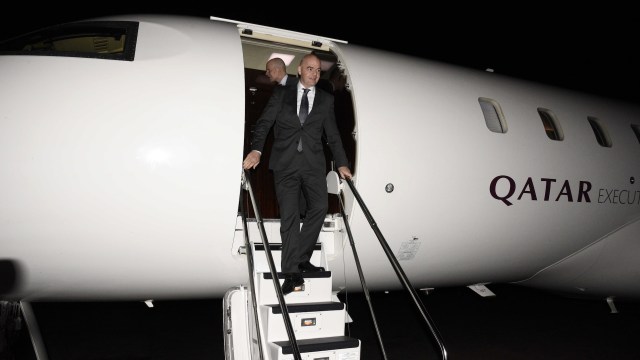 A man in a suit descends the steps of a private jet at night, with the Qatar Executive logo visible.