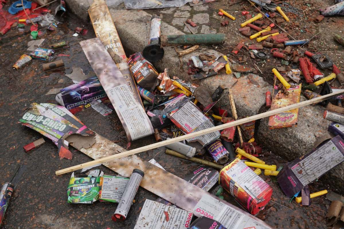 A cluttered ground littered with discarded firework packaging and debris.