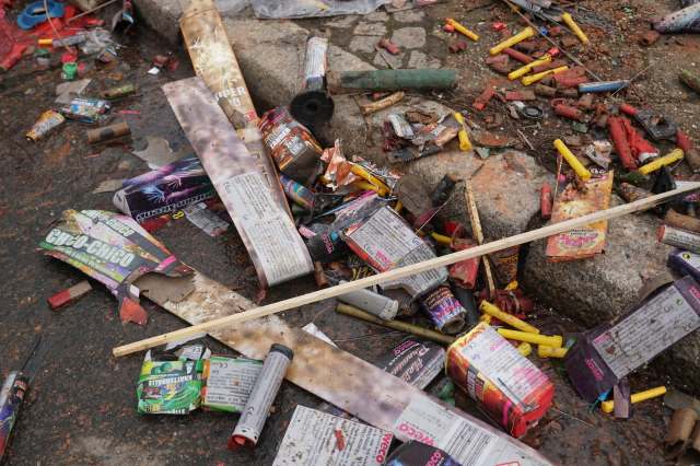 A cluttered ground littered with discarded firework packaging and debris.