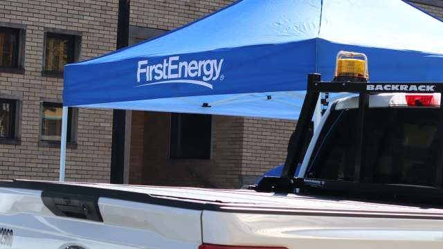 A blue tent with the FirstEnergy logo set up near a white pickup truck.