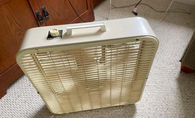 A Kmart box fan sitting on a carpeted floor.
