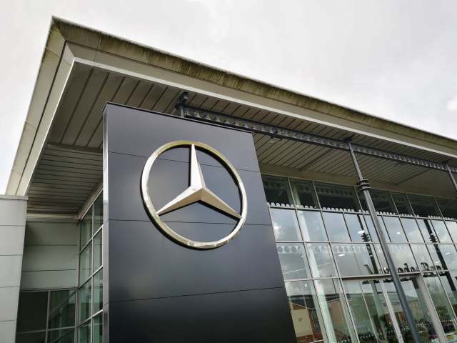 A close-up of a building exterior featuring the Mercedes-Benz logo on a modern structure.